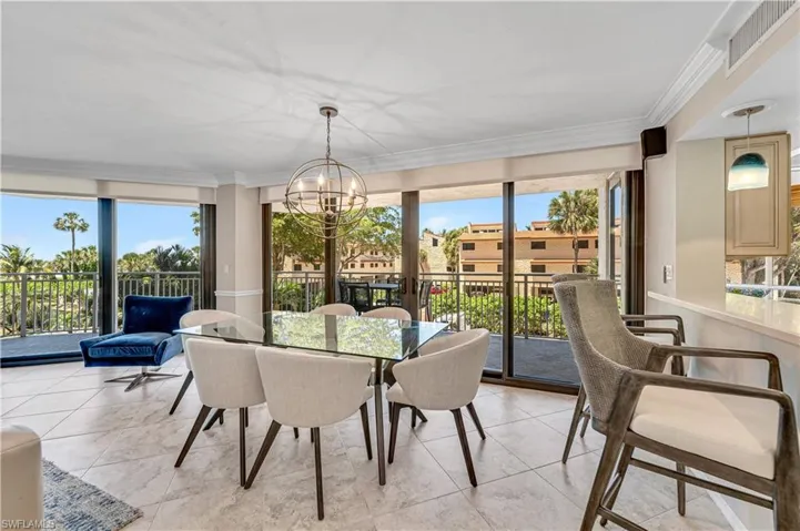 Sunroom with plenty of natural light, crown molding, a chandelier, and tile patterned flooring