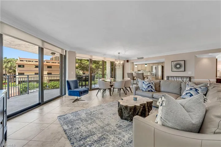 Tiled living room featuring a chandelier, crown molding, and floor to ceiling windows