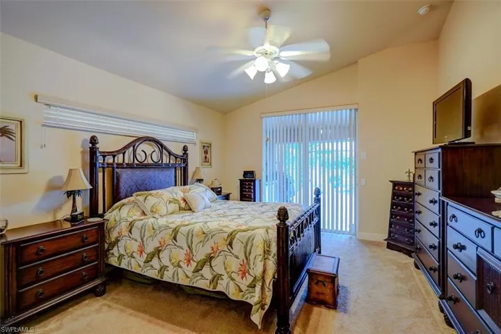 Carpeted bedroom with lofted ceiling and ceiling fan