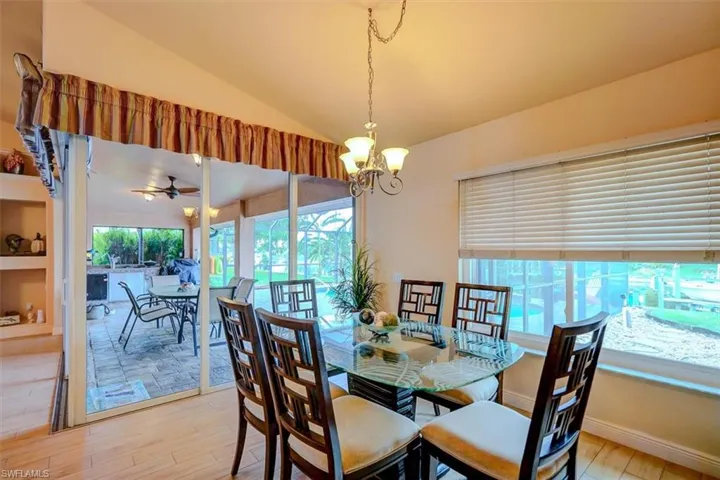 Dining area with ceiling fan with notable chandelier, light hardwood / wood-style flooring, and vaulted ceiling