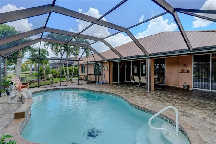 View of pool with glass enclosure and a patio area