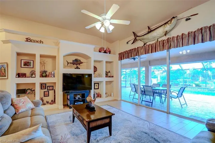 Living room with light wood-type flooring, vaulted ceiling, ceiling fan, and built in features