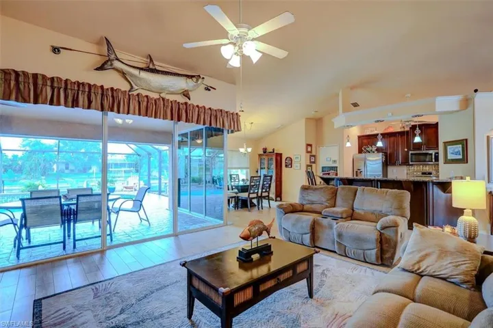 Living room featuring light wood-type flooring, vaulted ceiling, and ceiling fan