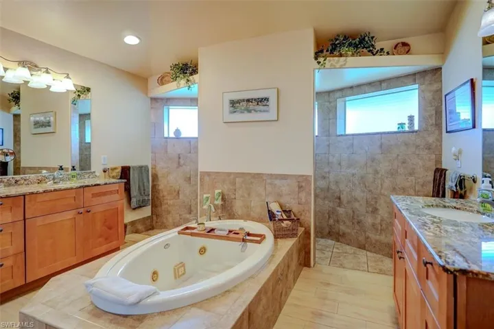 Bathroom featuring independent shower and bath, a healthy amount of sunlight, and vanity