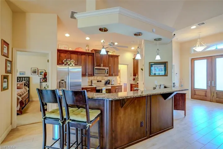 Kitchen featuring pendant lighting, a breakfast bar area, stainless steel appliances, and light stone countertops