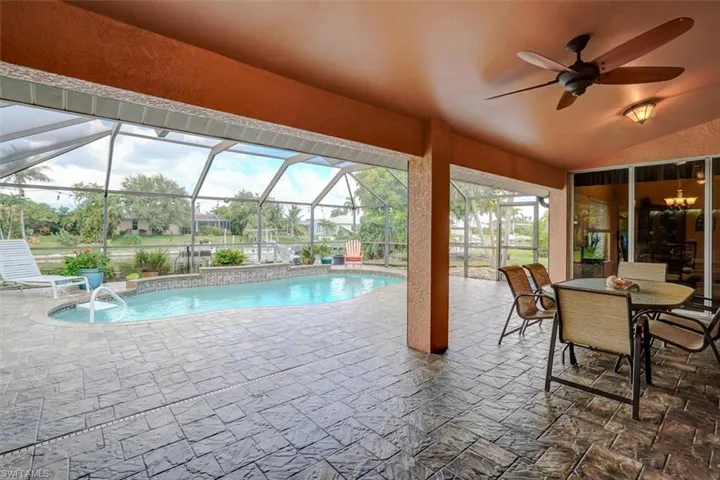 View of pool featuring a lanai, a patio, ceiling fan, and pool water feature