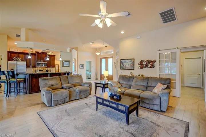 Living room with ceiling fan, lofted ceiling, and light hardwood / wood-style floors