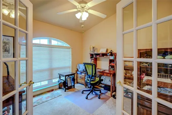 Carpeted office with lofted ceiling, ceiling fan, and french doors