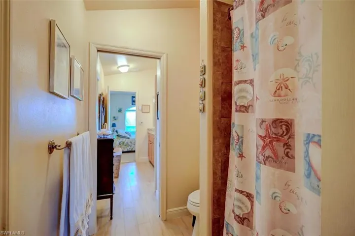 Bathroom with wood-look tile flooring, lofted ceiling, curtained shower, and toilet