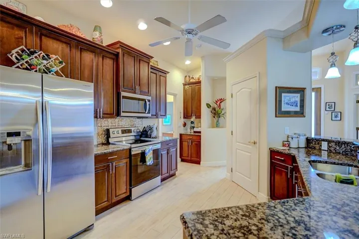 Kitchen with backsplash, stainless steel appliances, light wood-type flooring, ceiling fan, and decorative light fixtures