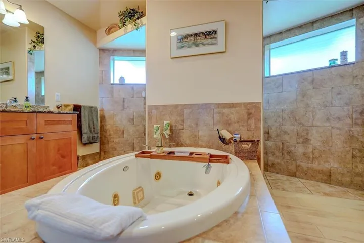 Bathroom featuring tiled bath and vanity