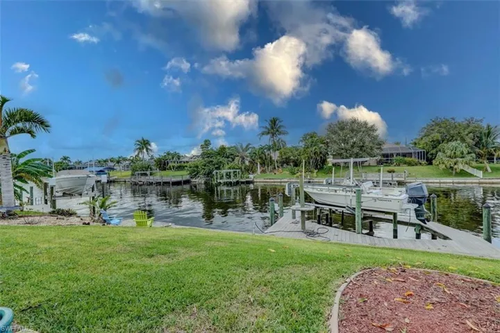 View of dock featuring a lawn and a water view