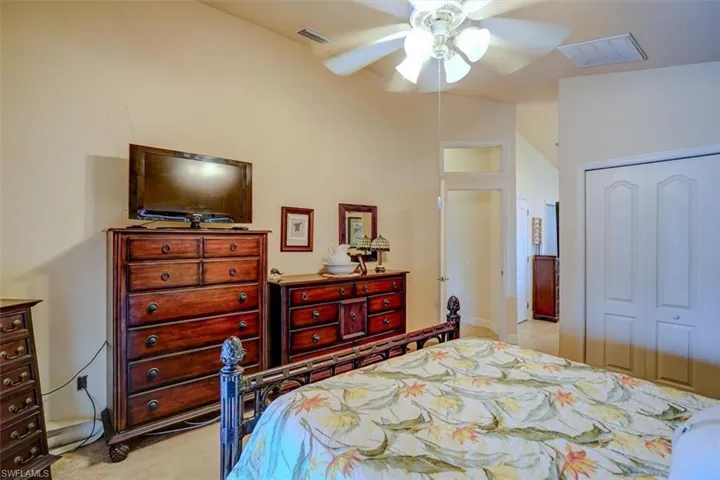 Bedroom featuring lofted ceiling, a closet, light colored carpet, and ceiling fan