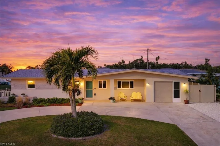 Single story home featuring curved driveway, a metal roof, stucco siding, and a gate