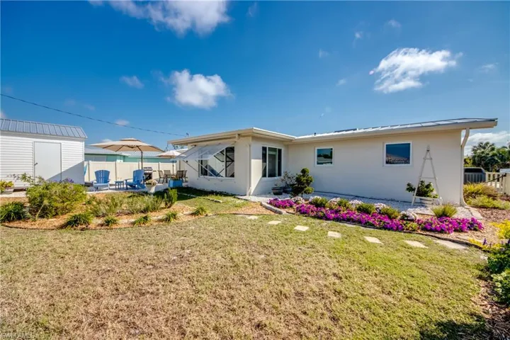 Back of property with a patio area, a storage unit, and stucco siding