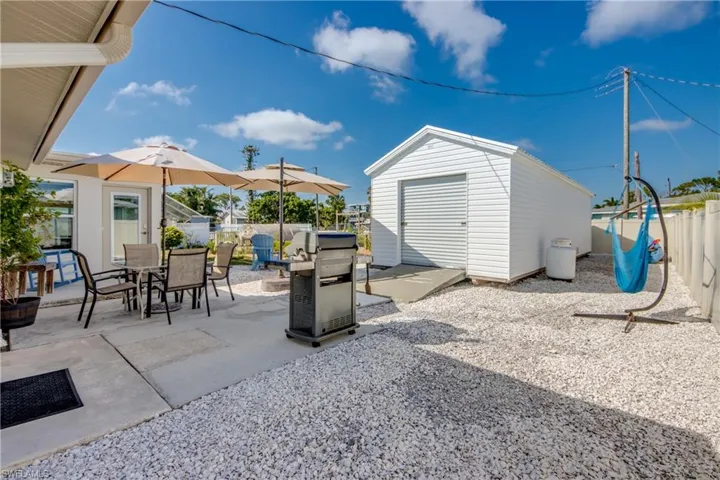 Fenced backyard featuring a patio, an outbuilding, and outdoor dining space