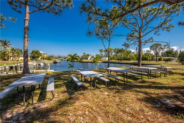 Surrounding community with a water view and a lawn