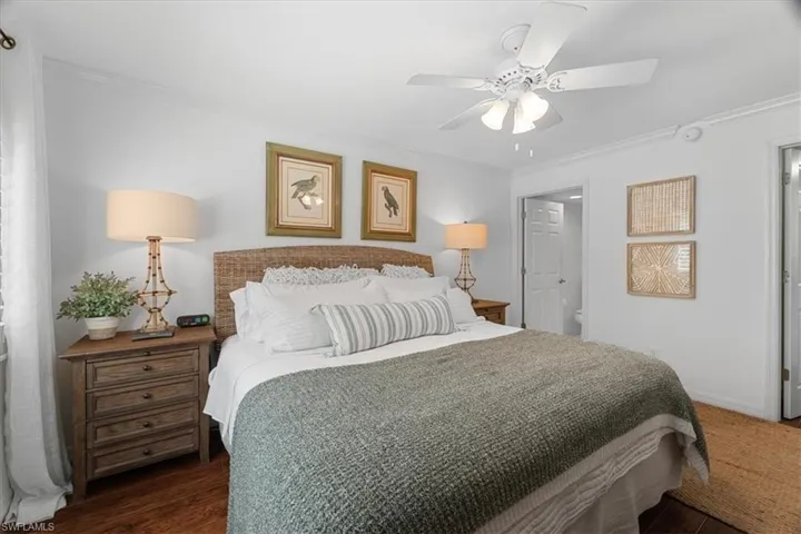 Bedroom with a ceiling fan, baseboards, dark wood-type flooring, and ornamental molding