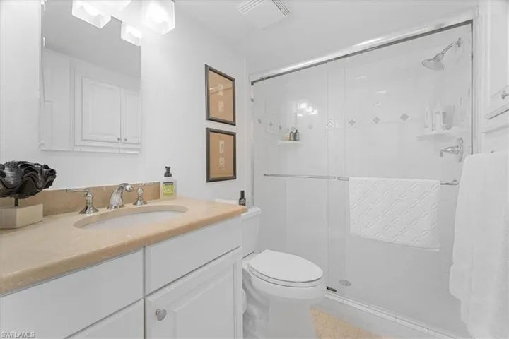 Full bathroom featuring tile patterned floors, visible vents, toilet, vanity, and a stall shower