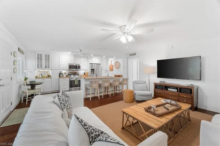 Living room with dark wood-style flooring, ceiling fan, and visible vents