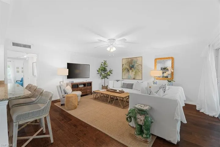 Living room featuring baseboards, wood finished floors, visible vents, and a ceiling fan