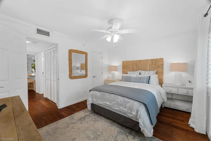 Bedroom with wood finished floors, visible vents, a ceiling fan, ornamental molding, and baseboards