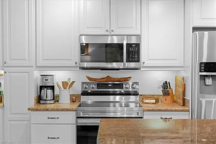 Kitchen featuring white cabinets, appliances with stainless steel finishes, and light stone countertops