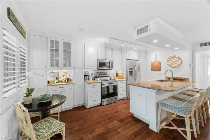 Kitchen with stainless steel appliances, a sink, dark wood-style flooring, visible vents, and white cabinetry