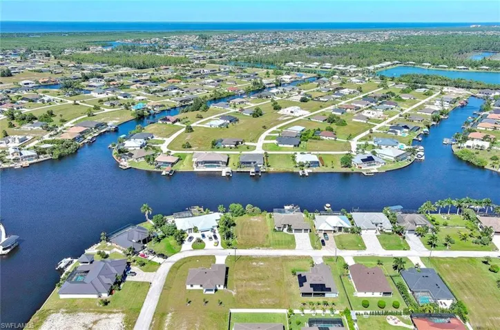 Aerial view of property and surrounding area featuring a nearby body of water and nearby suburban area