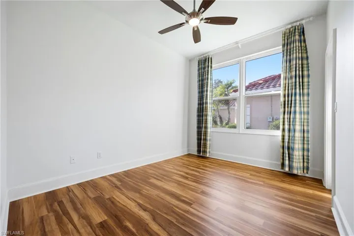 Unfurnished room featuring wood finished floors, ceiling fan, and lofted ceiling