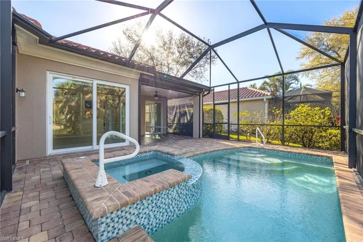 Combined pool / hot tub featuring a patio area, a sunroom, and glass enclosure