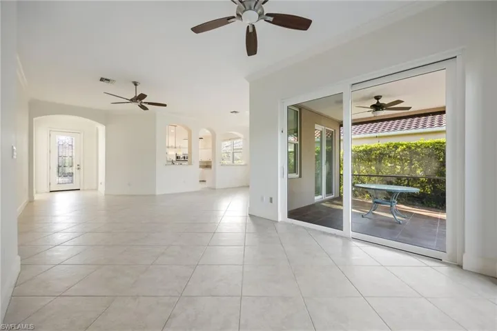Unfurnished room featuring a ceiling fan, crown molding, arched walkways, and light tile patterned floors