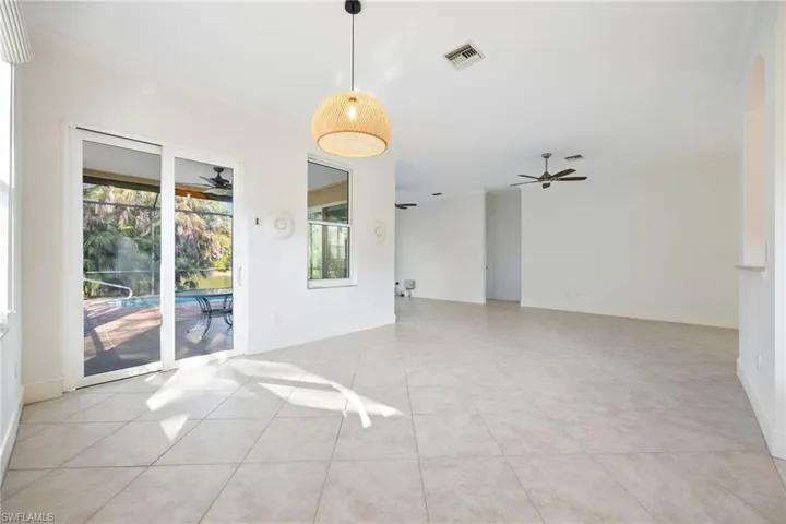 Empty room with crown molding, ceiling fan, a sunroom, and light tile patterned floors