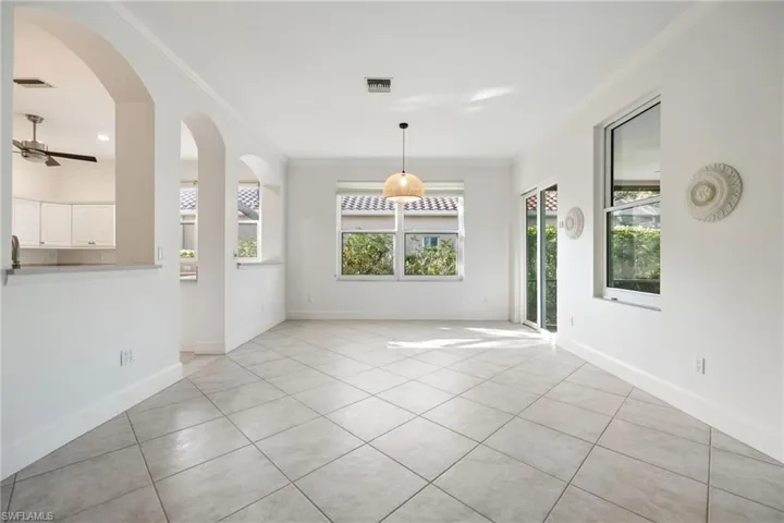 Unfurnished dining area featuring crown molding, light tile patterned floors, a ceiling fan, and arched walkways