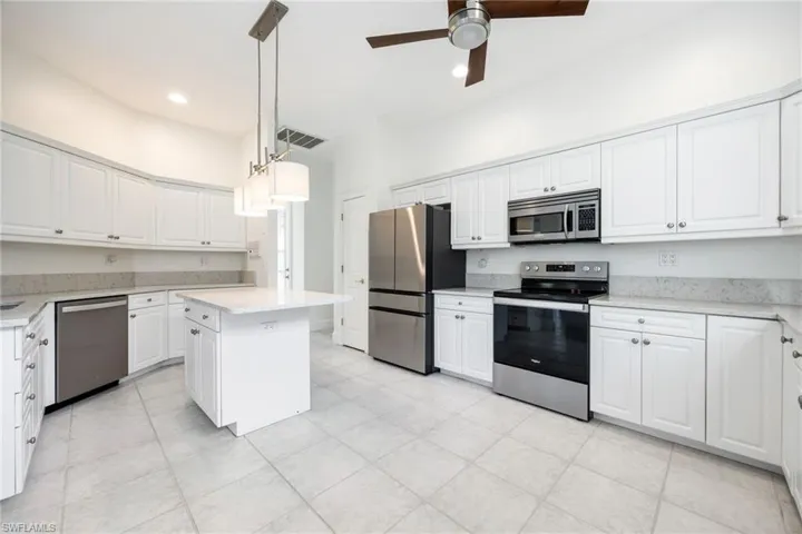Kitchen featuring stainless steel appliances, white cabinetry, a ceiling fan, and light stone countertops