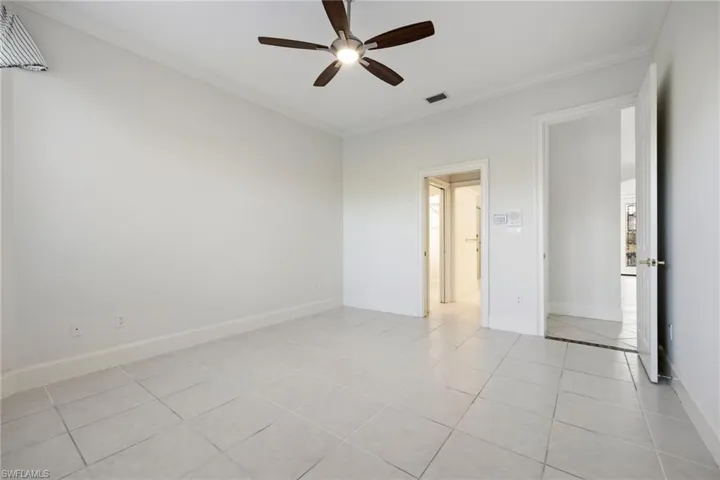 Unfurnished bedroom with ornamental molding, ceiling fan, and light tile patterned flooring
