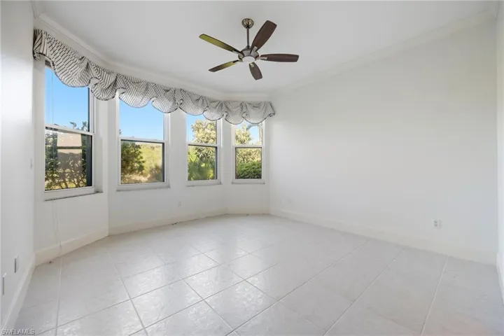 Spare room featuring crown molding, ceiling fan, and light tile patterned flooring
