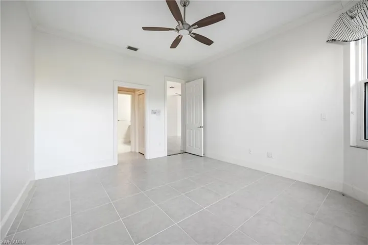 Unfurnished bedroom with crown molding, a ceiling fan, and light tile patterned floors