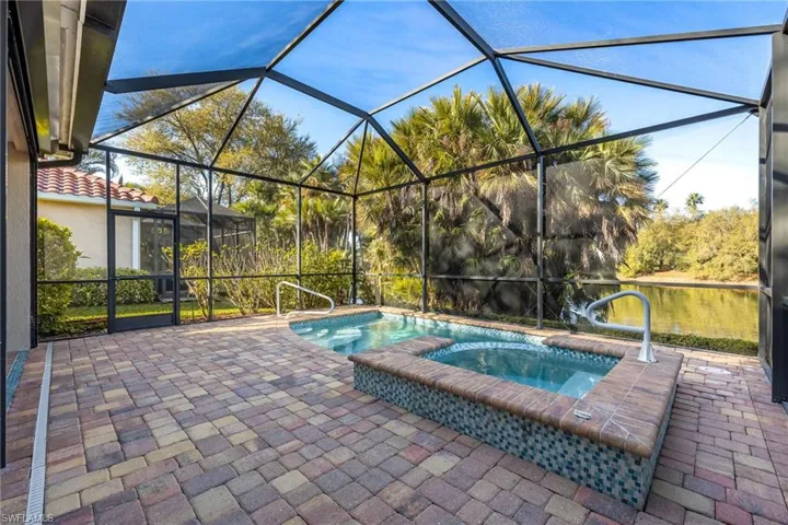 Relaxing pool / spa featuring a patio area, a sunroom, a water view, and glass enclosure