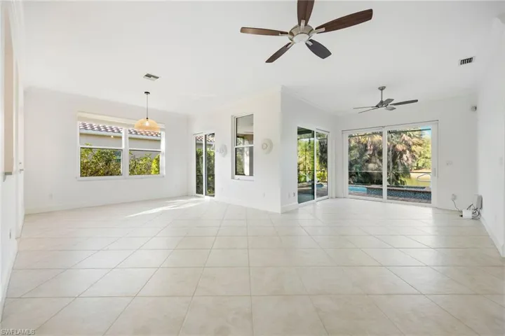 Spare room featuring crown molding, healthy amount of natural light, light tile patterned floors, and ceiling fan