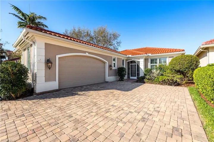 Mediterranean / spanish-style home featuring an attached garage, stucco siding, decorative driveway, and a tiled roof