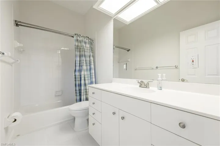 Full bathroom featuring vanity, shower / tub combo, light tile patterned floors, and a skylight