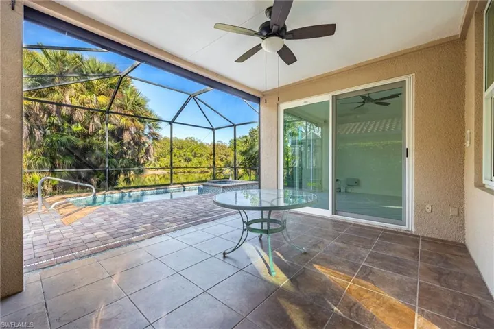 View of patio / terrace with a sunroom, a ceiling fan, glass enclosure, and a pool with connected hot tub