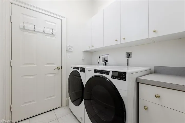Laundry area featuring cabinet space, light tile patterned floors, and washer and dryer