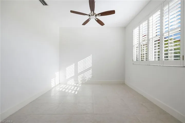 Empty room with ceiling fan and light tile patterned flooring