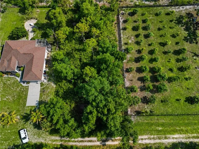 Expansive property featuring a single-story residence with a brown shingle roof, a concrete driveway, and a screened patio area