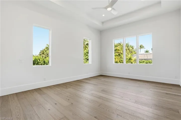 Spare room featuring a ceiling fan, light wood finished floors, a raised ceiling, and recessed lighting