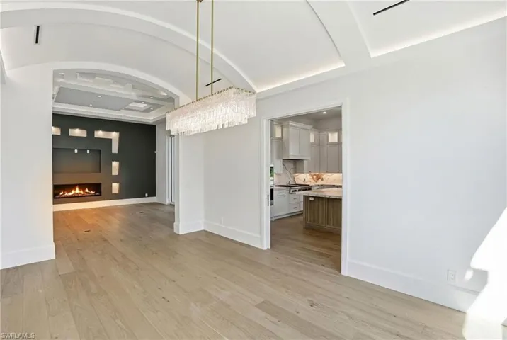 Unfurnished dining area featuring a lit fireplace and light wood-style flooring