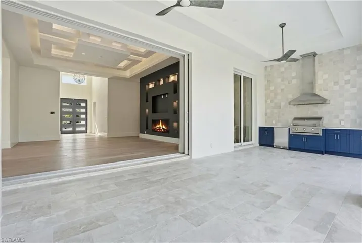 View of patio with area for grilling, ceiling fan, a large fireplace, and french doors