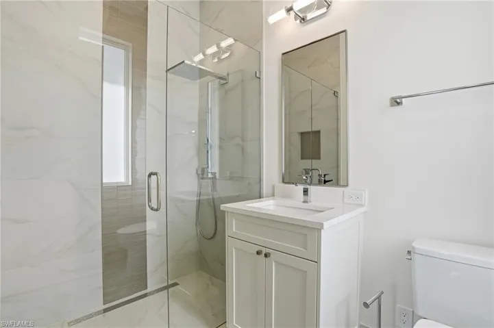 Bathroom featuring vanity and a marble finish shower